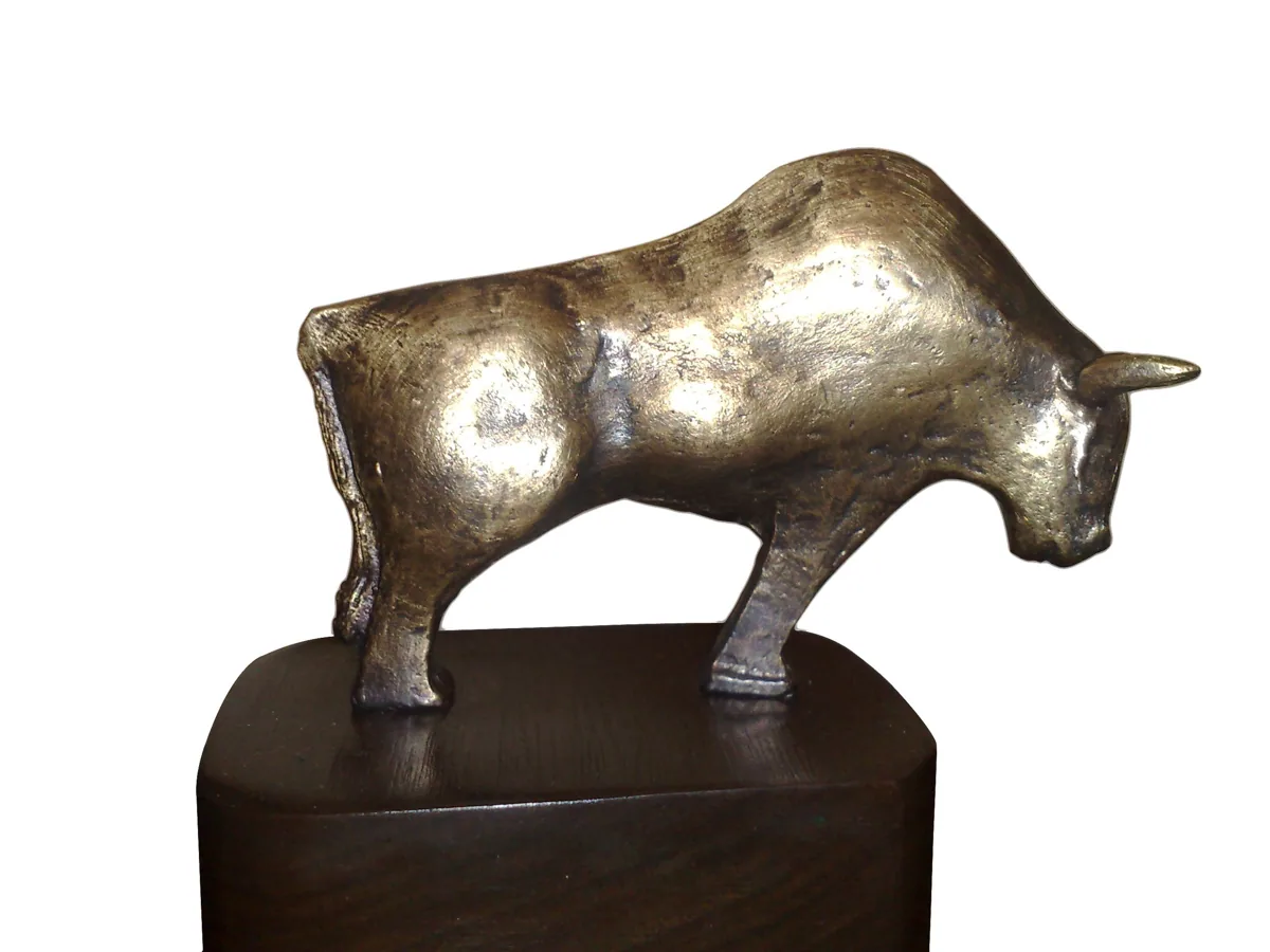 برونز A8، ⁦2007–2008.⁩ برونز. ثور من البرونز المصقول واقف على قاعدة خشبية داكنة.